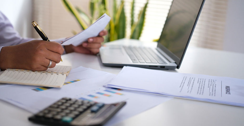 Bureau de planification de projet avec plans de rénovation, calculatrice et documents de chiffrage pour fenêtres dans un environnement de travail professionnel